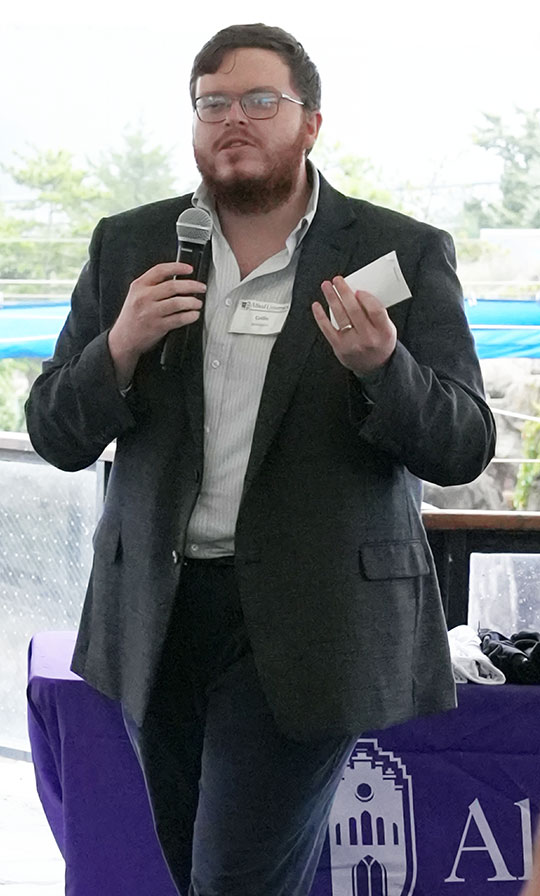 man with glasses and beard, no tie, talking with microphone