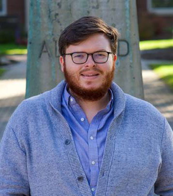 headshot of man in sweater, with glasses