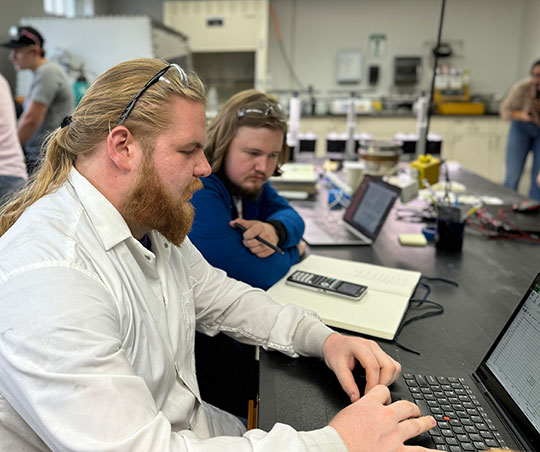 two men, with beards, looking at a laptop