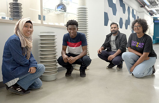 four young men and women posing in front of large ceramic insulators