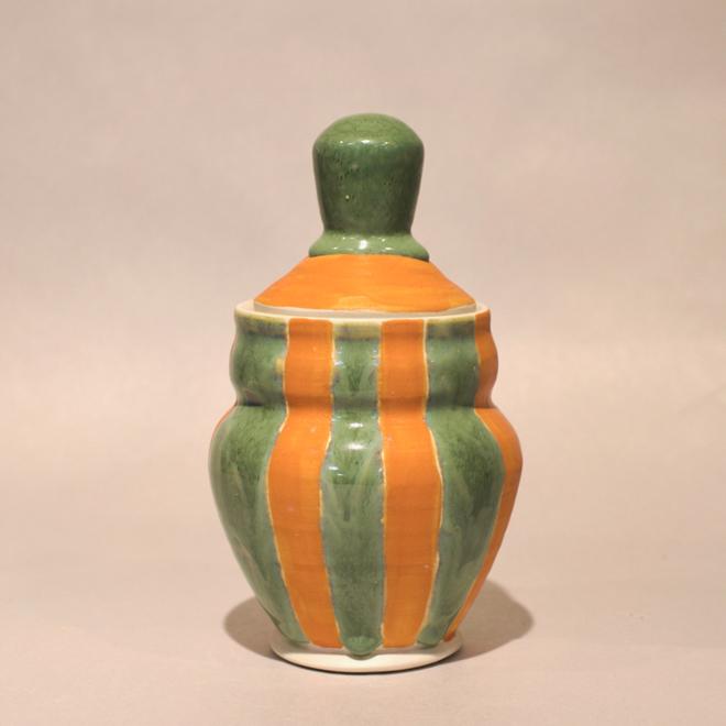A lidded jar with green and range stripes. 