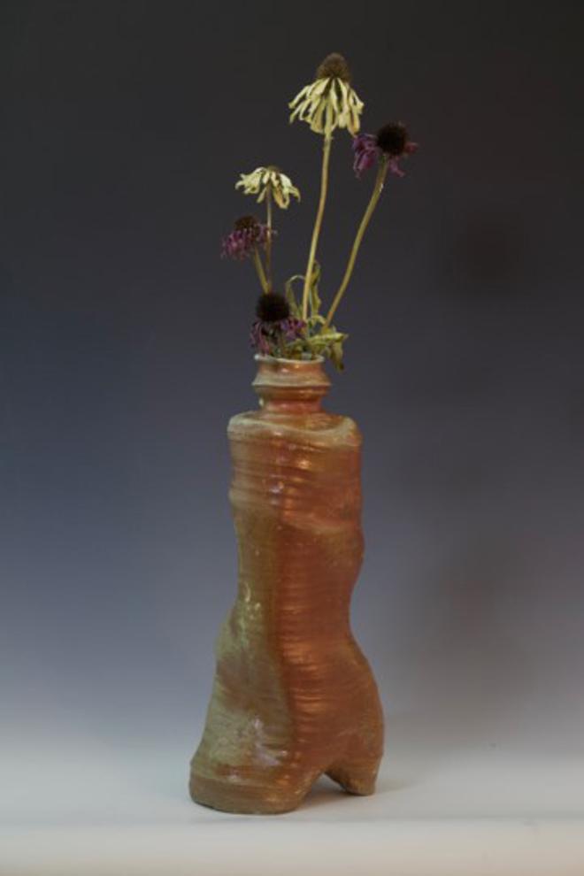 Tall, wonky ceramic vase with flowers.