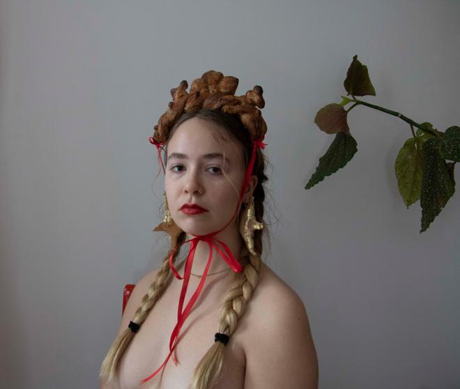 Bare chested woman with hair in braids, wearing headband made of bread.