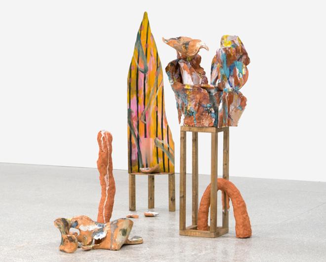 An abstract sculpture consisting of elements placed upon wooden pedestals and on the surrounding floor, organic shapes and bright colors.