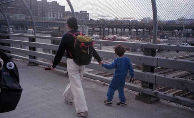 A photograph of a woman and child walking while holding hands.  