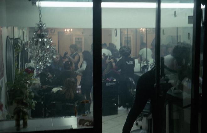 A photograph of the inside of a hair salon, taken from the outside window. 