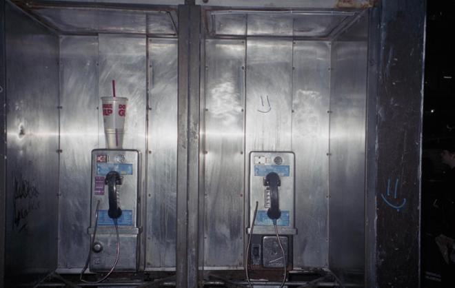 A photograph of two payphones in the dark. 