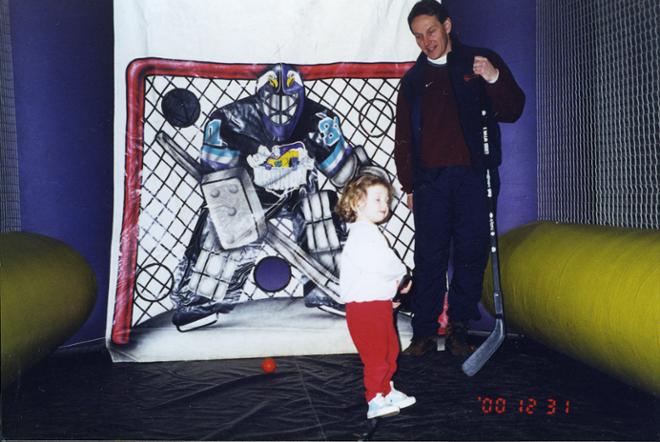A photograph of a child and a man in a hockey rink for children. 