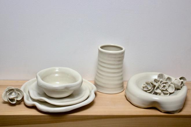 A grouping of ceramic dishes, vases, and ceramic flowers. 