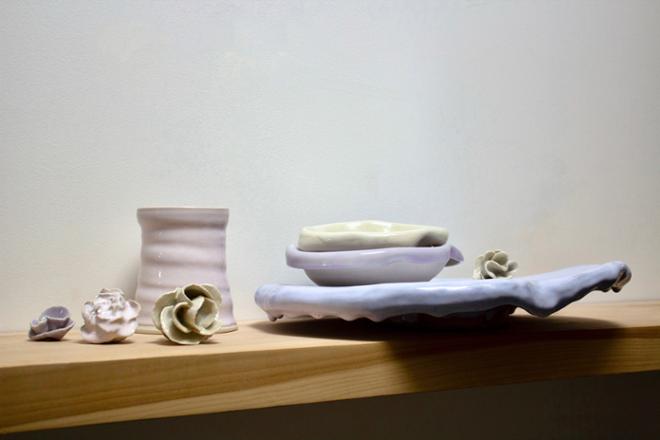 Ceramic vases and dishes spread out on a table with ceramic flowers. 