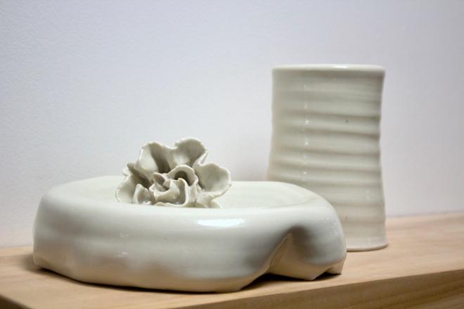 A ceramic flower sitting on a ceramic dish. 