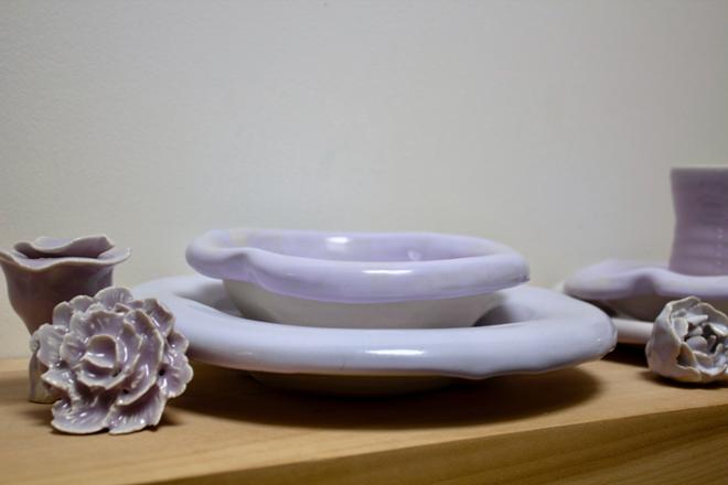 A grouping of ceramic dishes and flowers. 