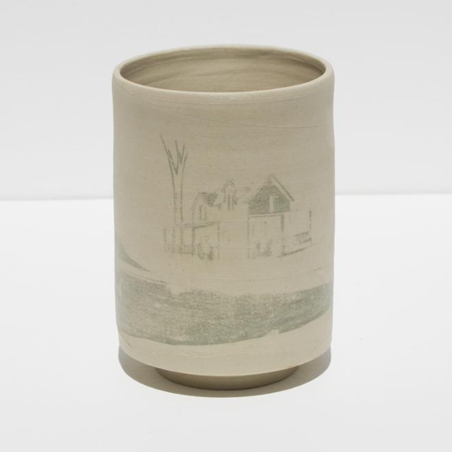 A ceramic cup with a building detailing on side.