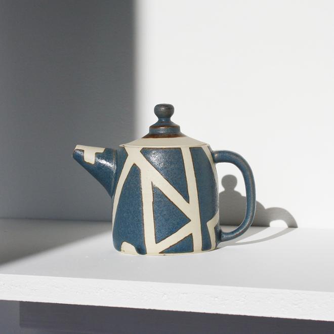 A ceramic teapot with blue and white glaze detailing 