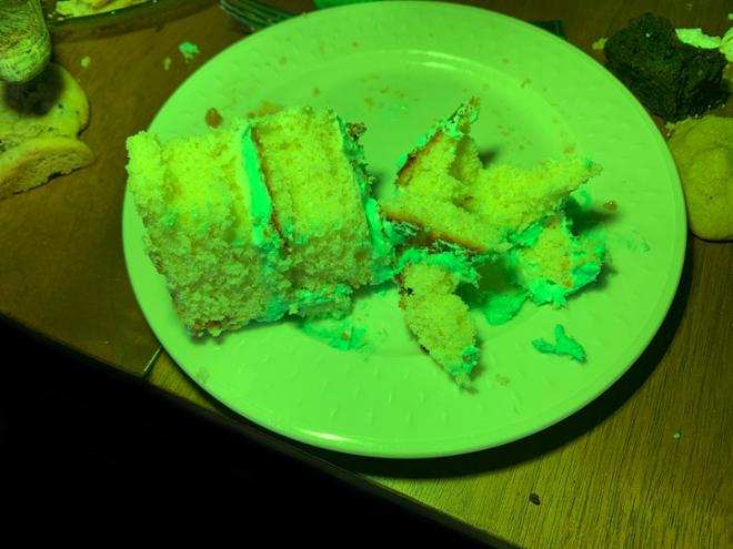 A green tinted image of a piece of cake on a table. 