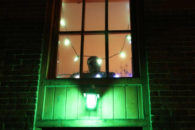 A photograph of a person looking out a window at night
