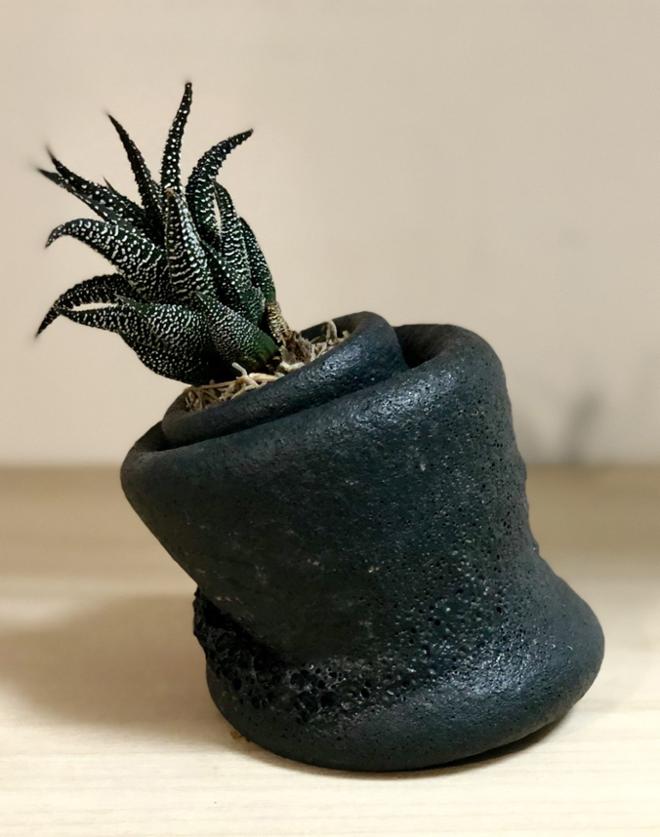 A leaning pot with a smaller pot inside of it. 