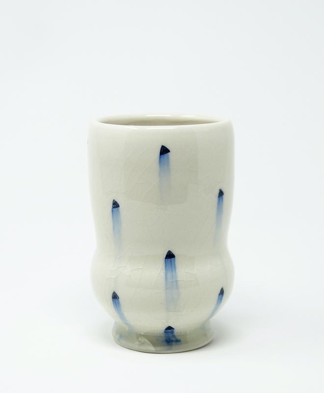 A white ceramic cup with blue dots. 