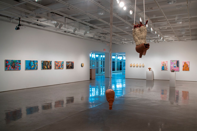 art gallery showcasing various sculptures and paintings both suspended from the ceiling, on platforms, and hanging on the wall
