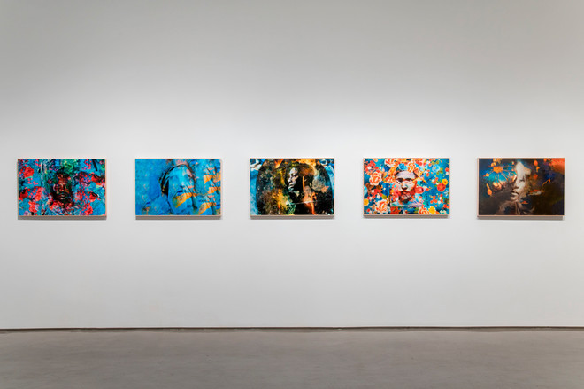 display of five paintings hanging on a gallery wall