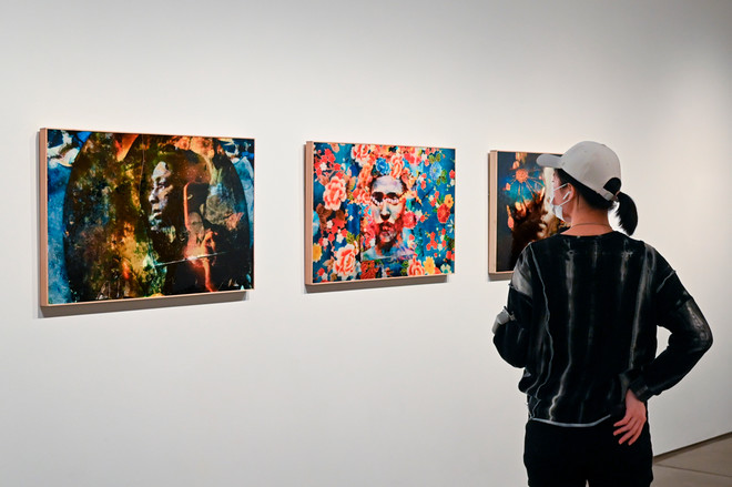 an individual viewing a display of three paintings