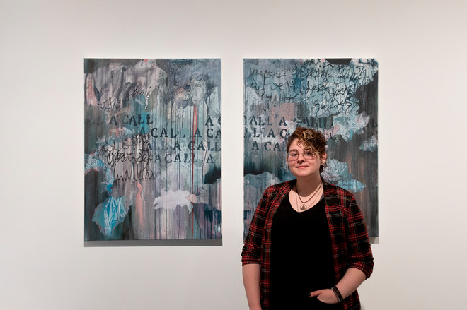 an individual standing next to two paintings
