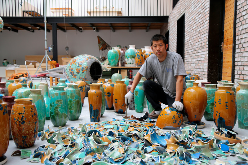 picture of artist surrounded by ceramic vessels